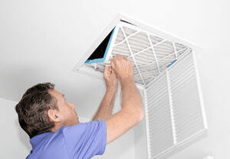 Man changing air filter for central AC system.